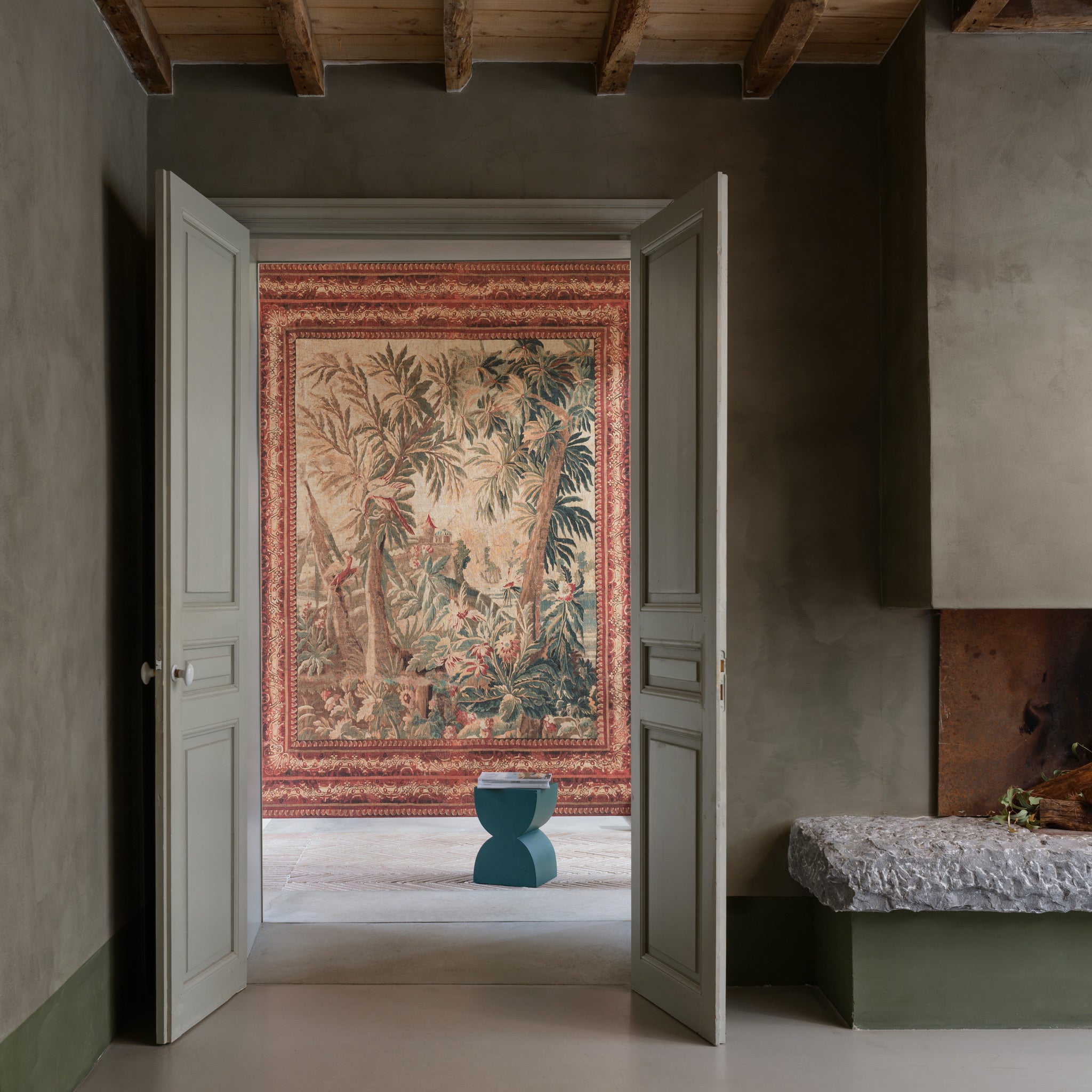 Decorative tapestry on a wall in a room with open doors.