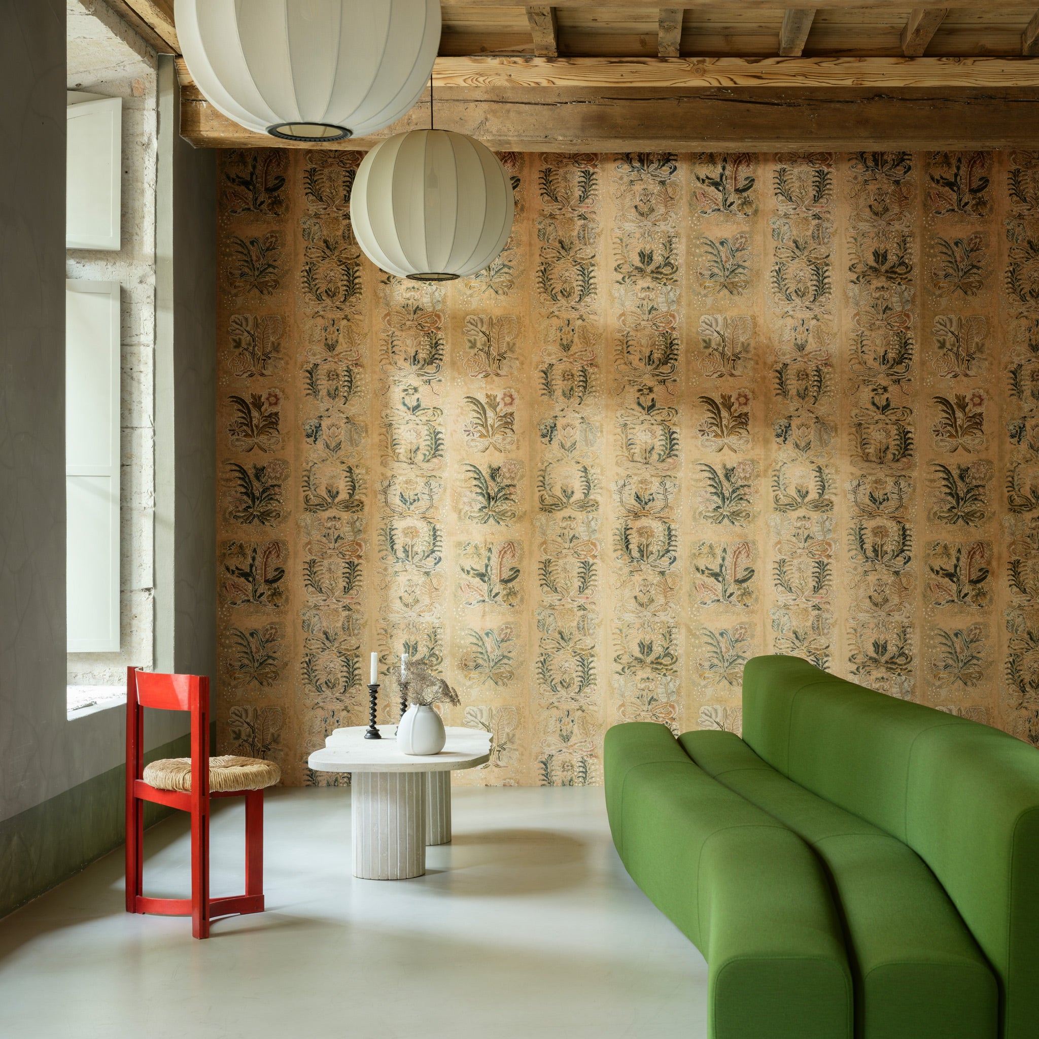 Modern interior with a green sofa, red chair, and patterned wall.