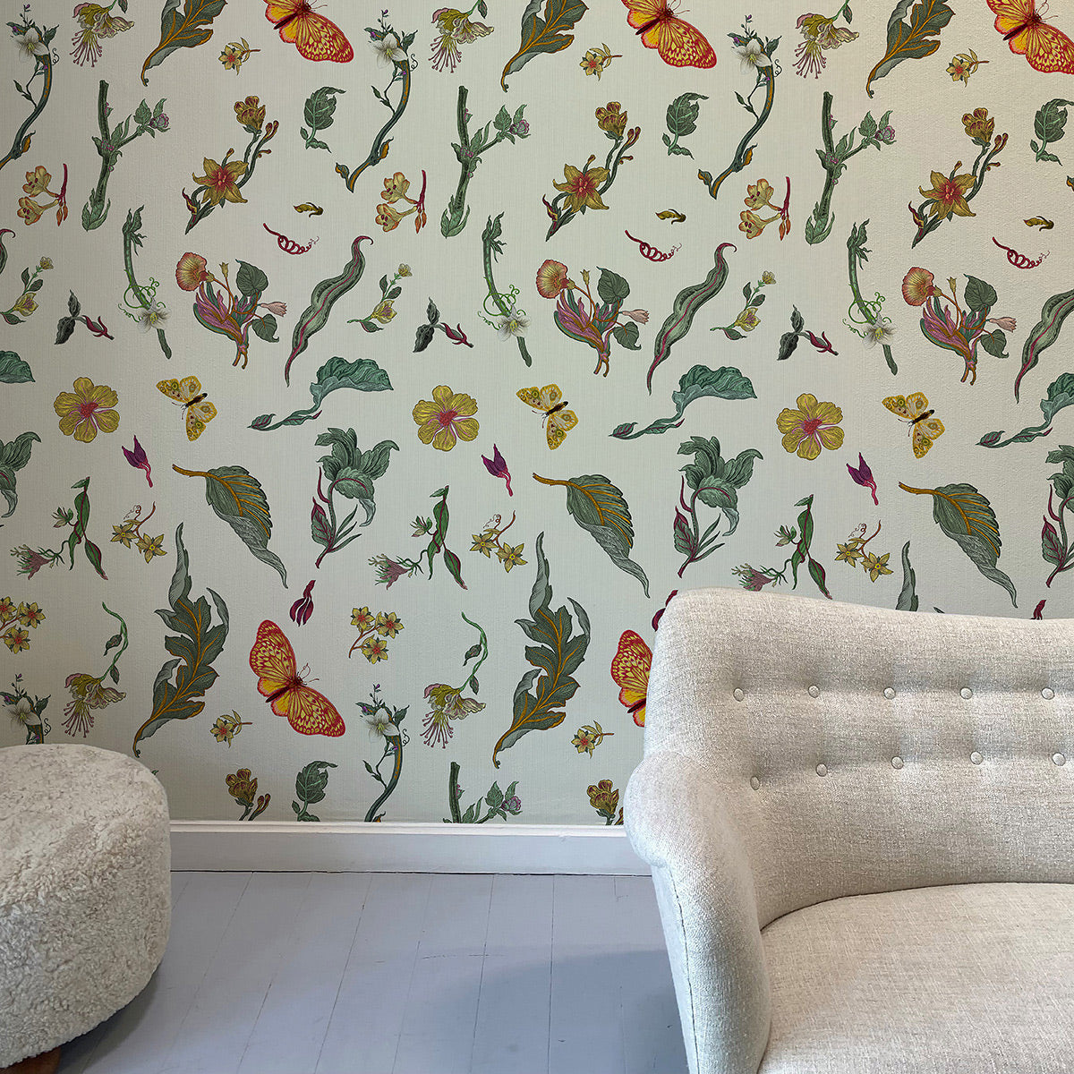 Room interior with floral and fairy wallpaper and a beige sofa.