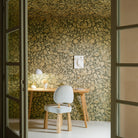 Room with floral wallpaper, wooden table, and chair.