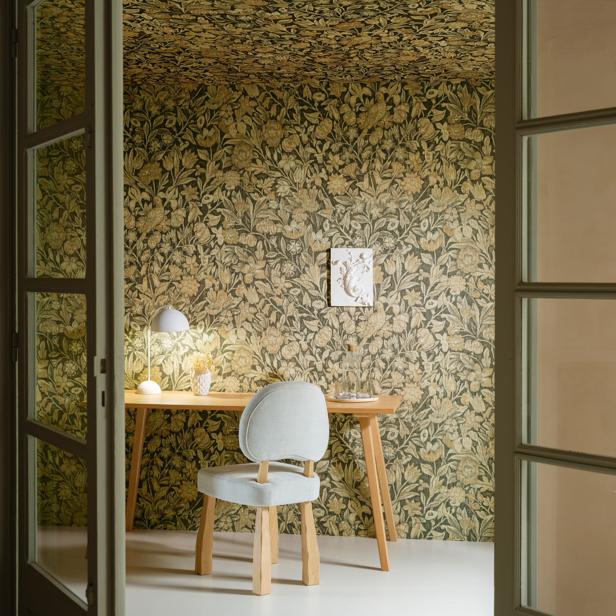 Room with floral wallpaper, wooden table, and chair.