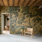Room with tapestry wall featuring a landscape scene, wooden chair, and table.