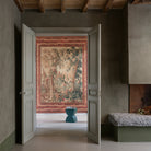 Decorative tapestry on a wall in a room with open doors.