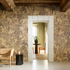Room with floral wallpaper, wooden furniture, and a stone archway leading to another room.